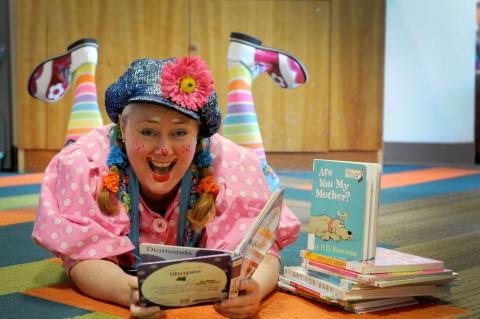 Sparkles reading library books on the floor of a library